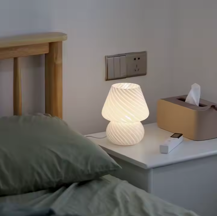 Un lit et une table de chevet et lampe de chevet champignon en verre