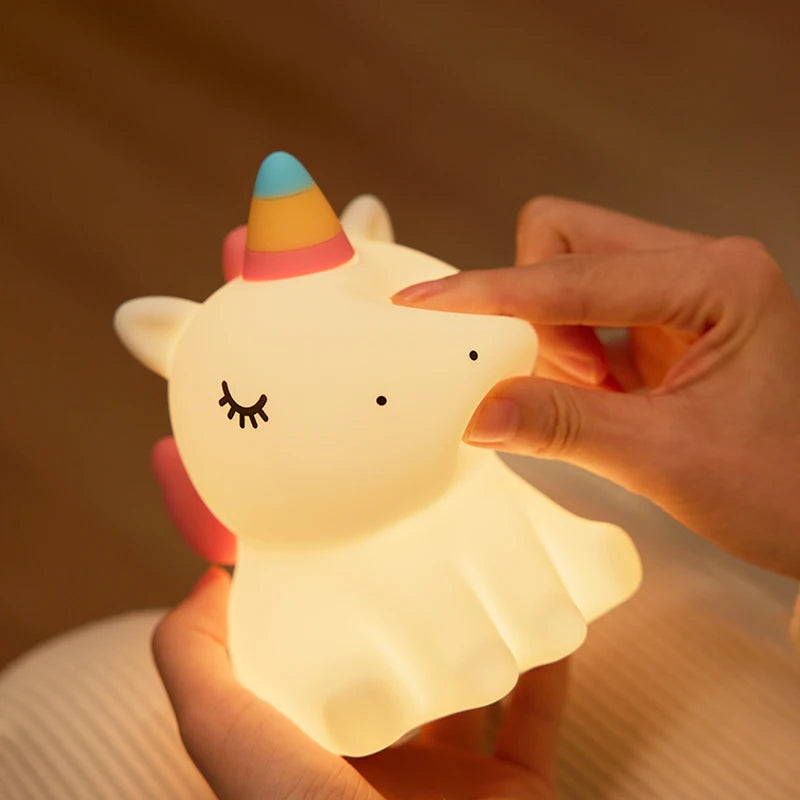 Une main qui pince la veilleuse bébé licorne