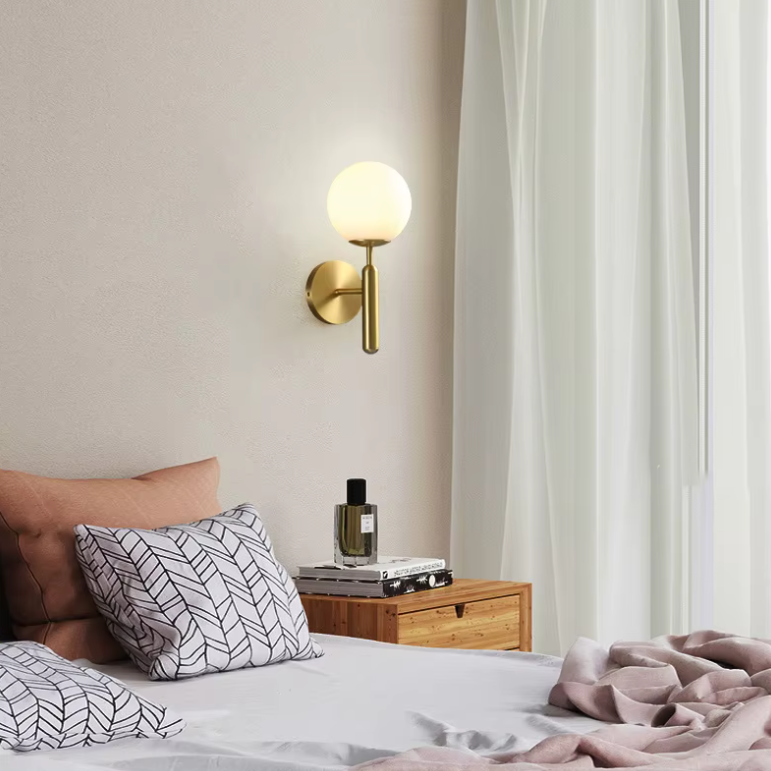 Applique murale dorée en métal dans une chambre à coucher blanche 