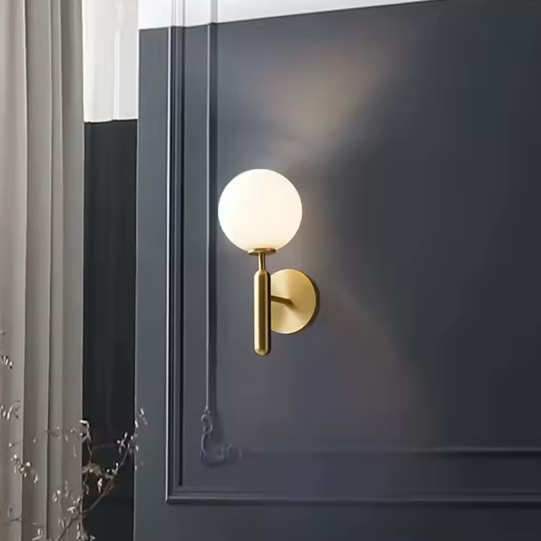 Applique murale dorée en métal sur mur gris 