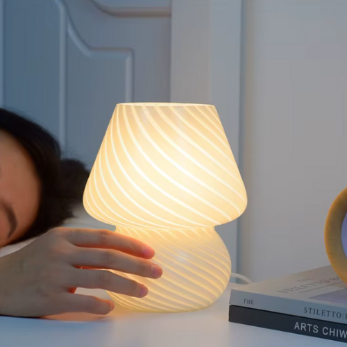 Lampe de chevet champignon en verre à côté d'une personne qui dort