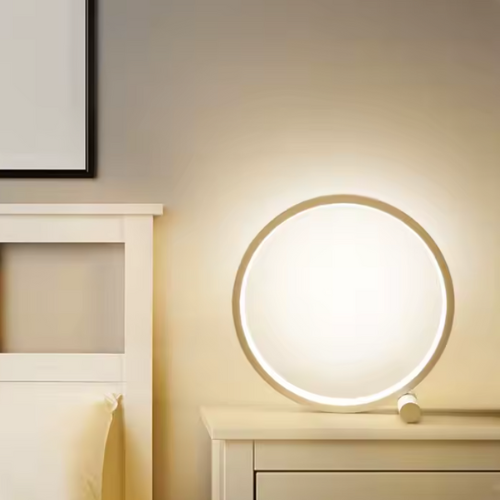 Lampe de chevet circulaire LED blanche sur table de chevet et lit blanc 