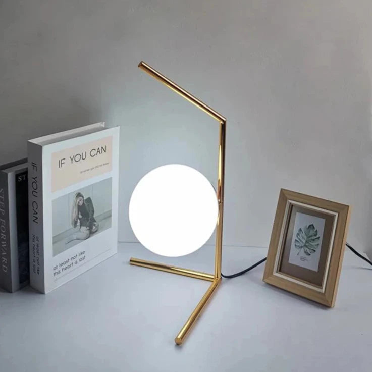 Lampe de chevet minimaliste nordique allumé un cadre et des livres à côté 
