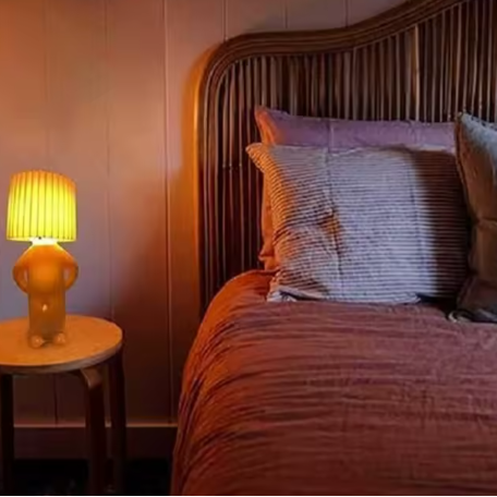 Lampe de chevet petit bonhomme sur table de chevet et lit 
