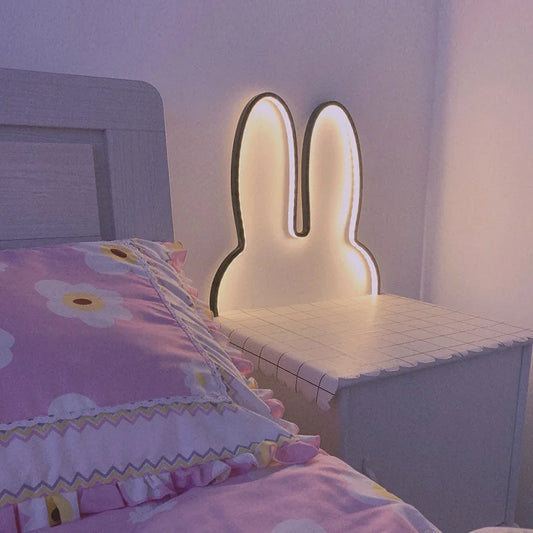 Lampe led lapin doré sur une table de chevet et un cousin rose 