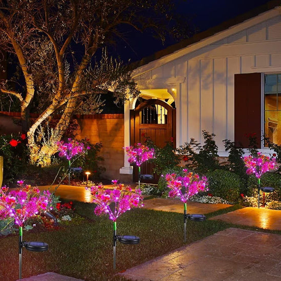 Lampe solaire extérieur en forme d'orchidée à côté d'un ardre ans un jardin 