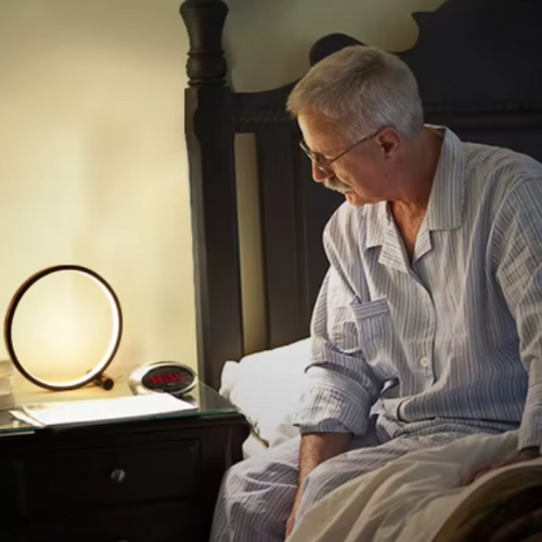 Un homme qui lit et la lampe de chevet circulaire allumé