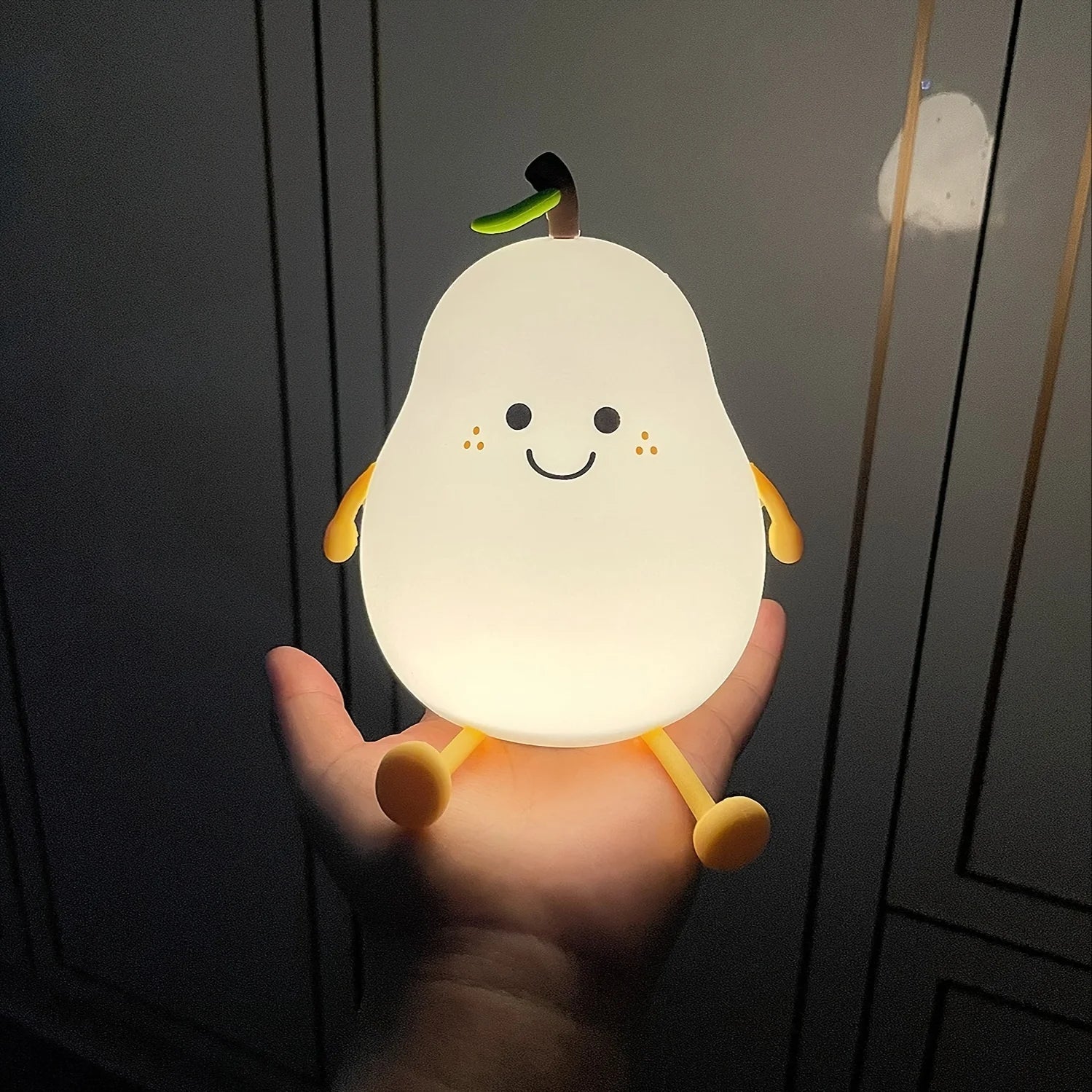 Une main qui porte veilleuse de nuit en forme de poire 